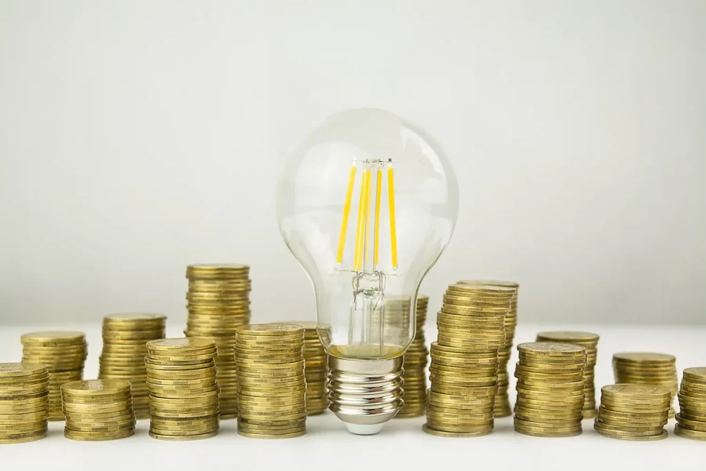 business concept lamp with coins on a light backg