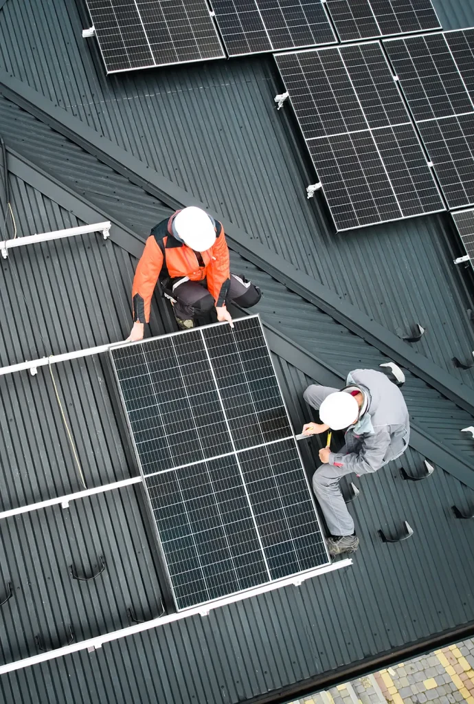 men workers installing solar panels on roof of house